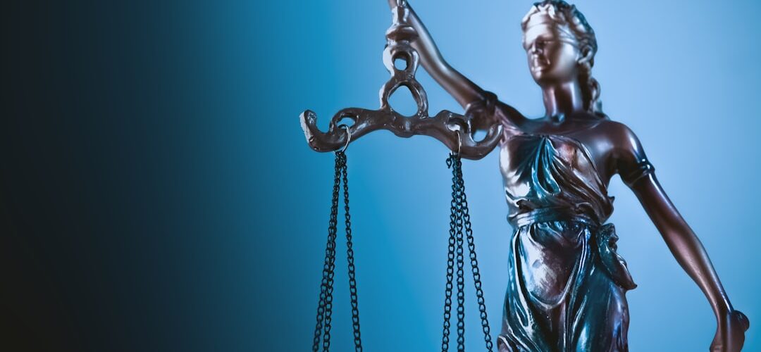 Statue of justice holding scales against blue background