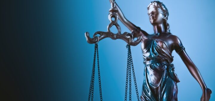 Statue of justice holding scales against blue background