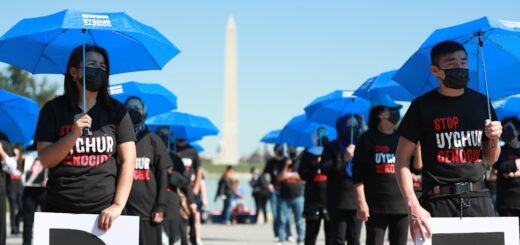 a group of people holding blue umbrellas in front of the washington monument