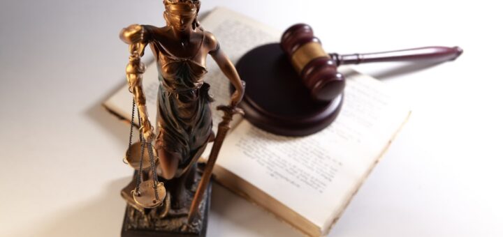 Statue of justice, gavel, and open book on table.